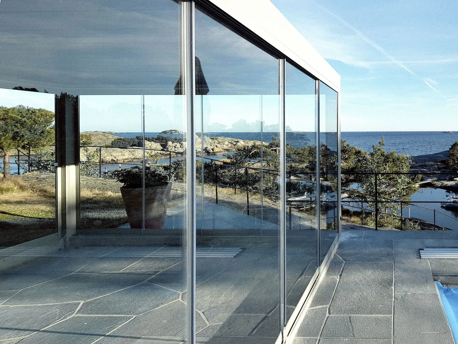 Pergola bioclimatica con chiusure laterali in vetro scorrevole per comfort tutto l'anno.