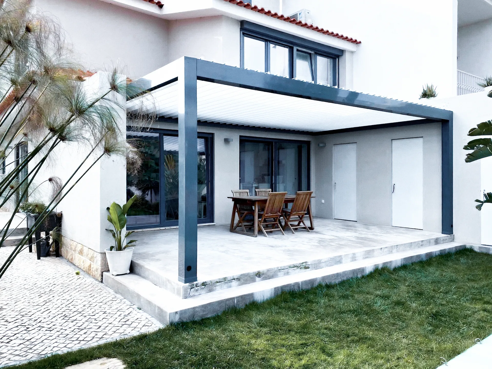 Pergola bioclimatica con struttura grigio antracite integrata perfettamente nell'architettura moderna.