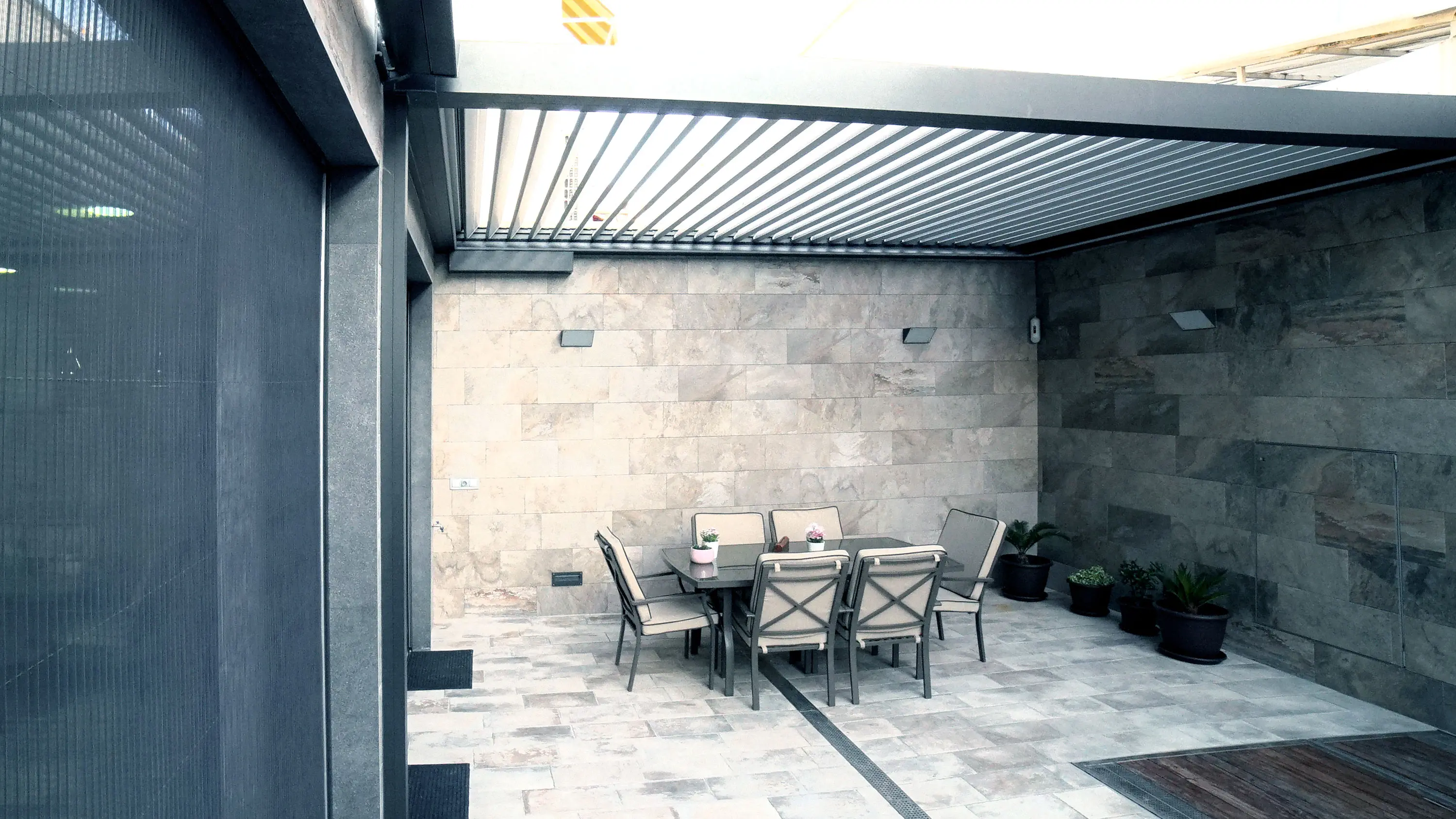 Dettaglio delle lamelle orientabili di una pergola bioclimatica durante la regolazione della luce.