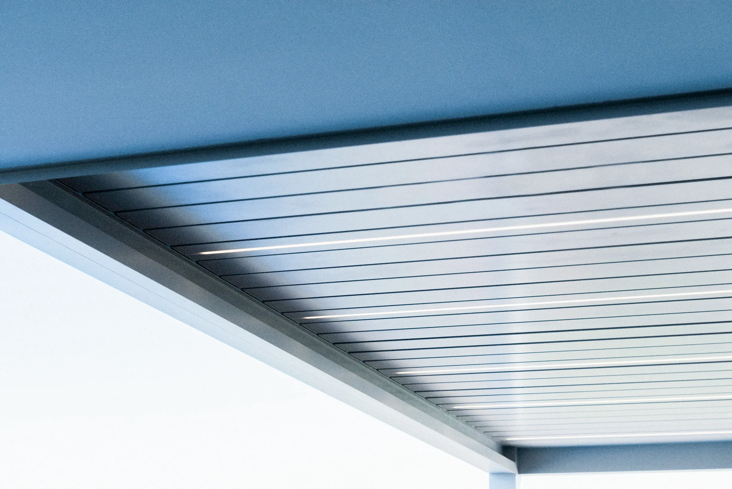 Pergolato bioclimatico moderno installato in un giardino con illuminazione LED integrata.