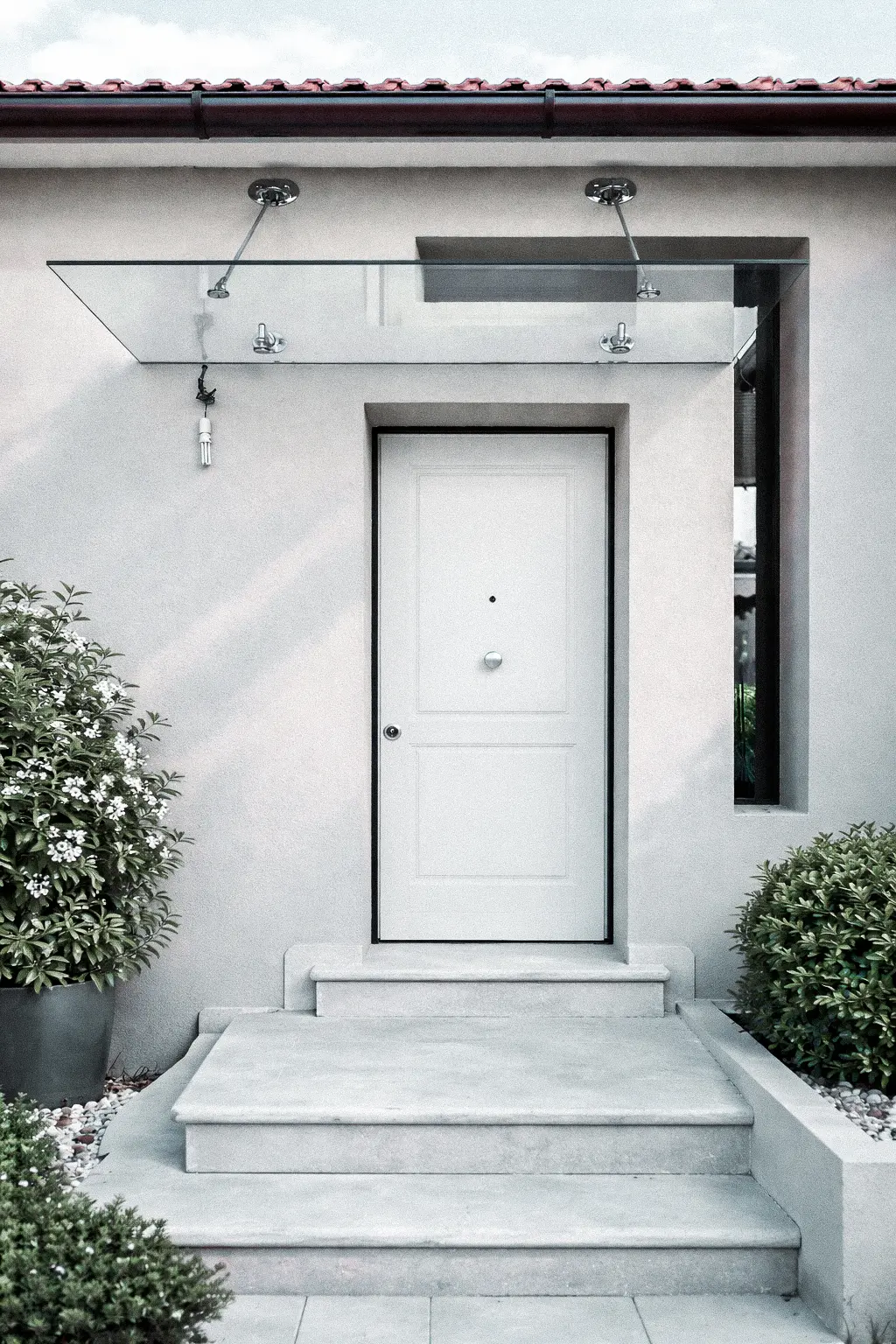 Pensiline in vetro e acciaio con supporti metallici di design per facciate esterne.